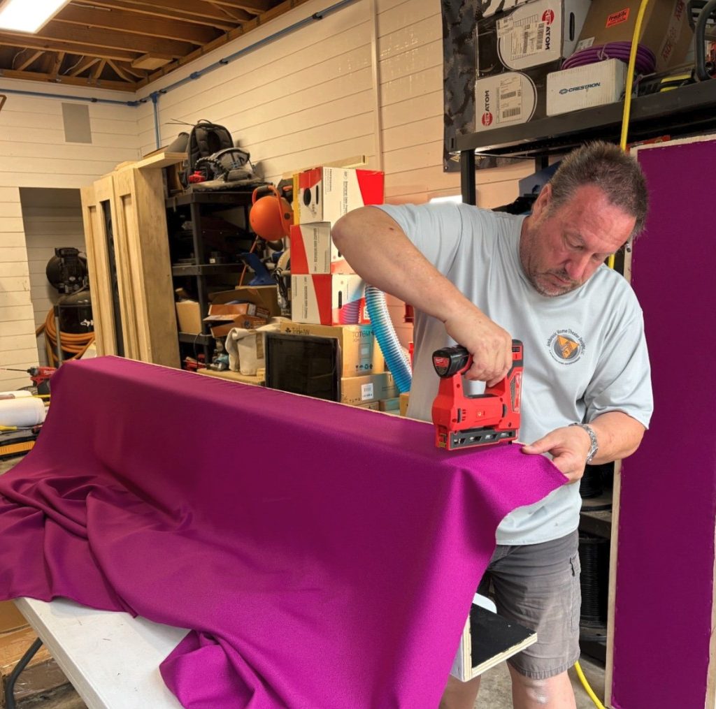 The client's selected color fabric wrap is being applied, adding a custom touch to the theater design.
