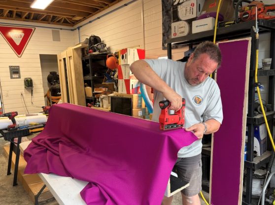 The client's selected color fabric wrap is being applied, adding a custom touch to the theater design.
